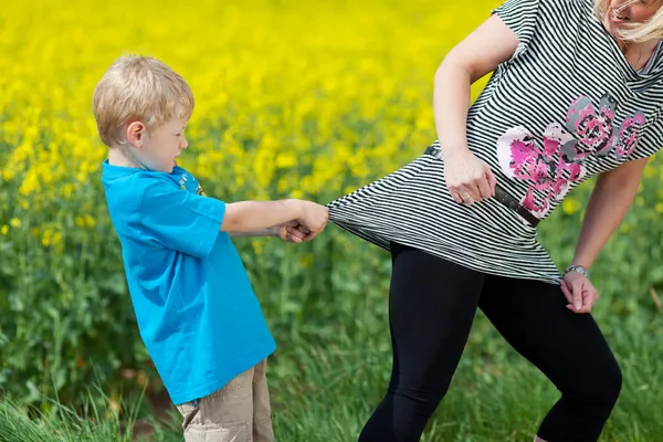 Pequeño niño enojado tirando de su camisa madres —  Fotos de Stock