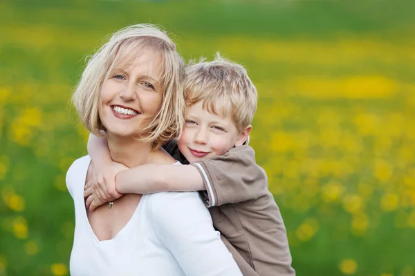 Glückliche blonde Frau trägt ihren Sohn — Stockfoto