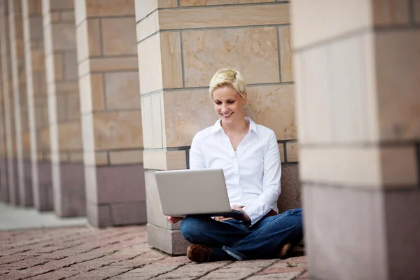 Siedzi blondynka kobieta z laptopa — Zdjęcie stockowe