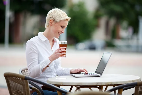 Vrouw met behulp van een laptop in een restaurant — Stockfoto