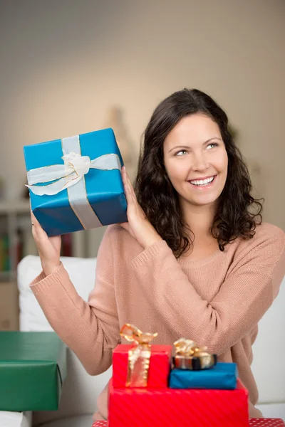 Happy woman guessing the contents of her gifts — Stock Photo, Image