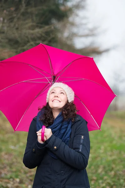 Kvinna i vinterkläder innehar rosa paraply — Stockfoto