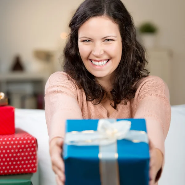 Lachende Frau hält ein buntes Geschenk in die Höhe — Stockfoto