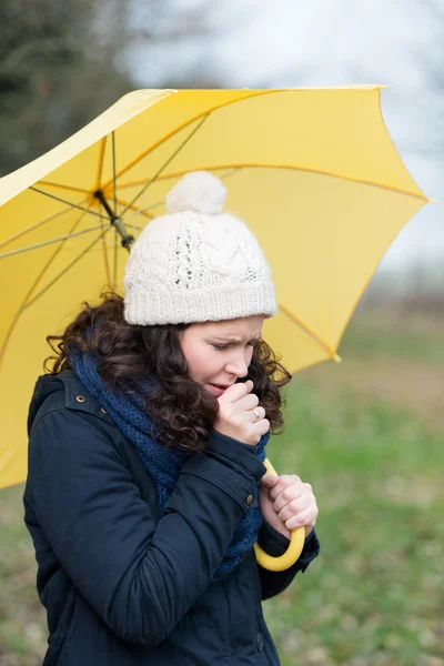 Woman walking under an umbrella coughing — Stock Photo, Image