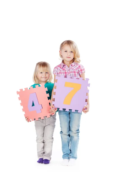 Meisjes houden nummer puzzel stukjes tegen witte achtergrond — Stockfoto