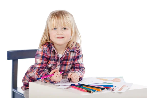 Маленькая девочка рисует, сидя за столом — стоковое фото