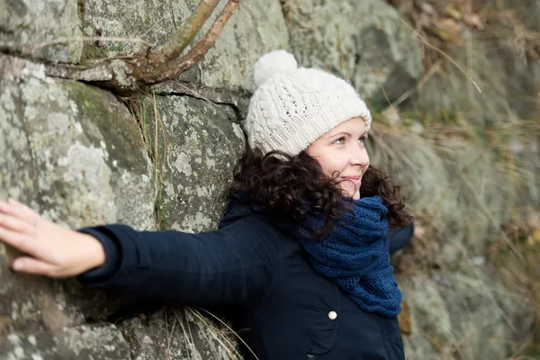 Donna in abiti invernali con le braccia distese appoggiate su Stonew — Foto Stock