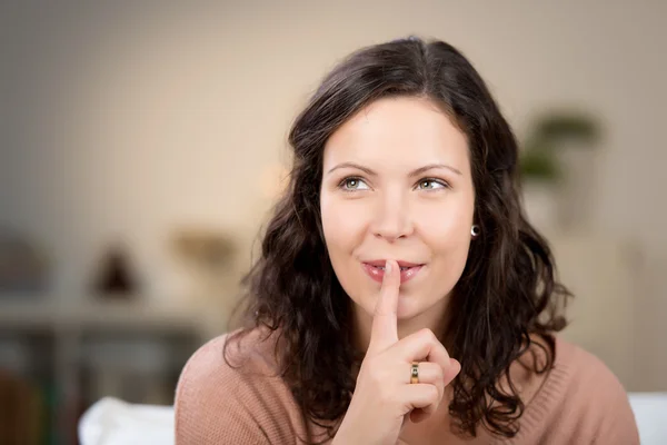 Vrouw met vinger op lippen thuis — Stockfoto