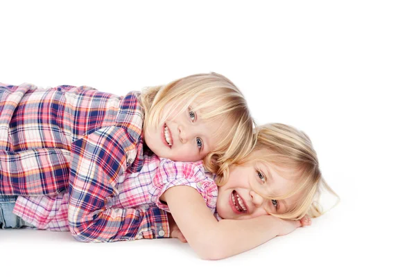 Mädchen liegt auf Schwester vor weißem Hintergrund — Stockfoto