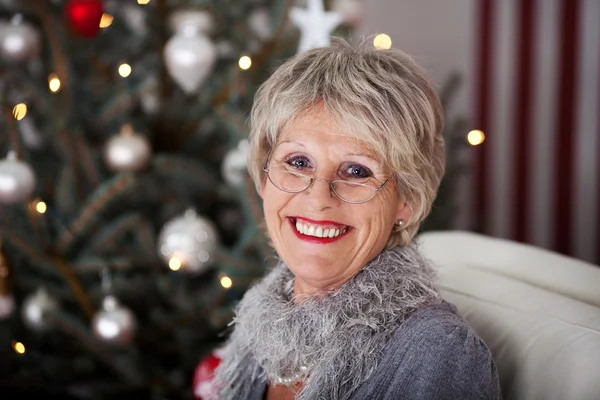 Señora mayor sonriente frente al árbol de Navidad — Foto de Stock