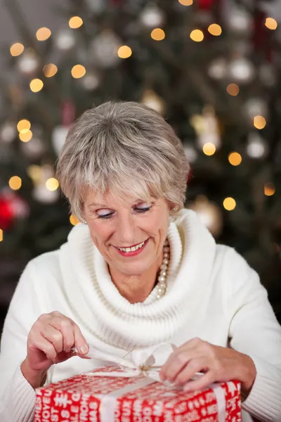Seniorin öffnet ihr Weihnachtsgeschenk — Stockfoto