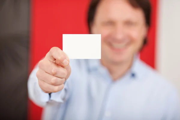Улыбающийся человек в магазине показывает белую карточку — стоковое фото