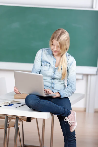 Studentka pomocí notebooku, zatímco sedí na stole — Stock fotografie