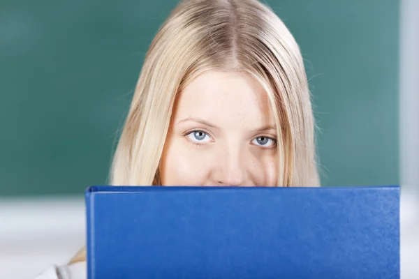 Vrouwelijke student met blauwe bindmiddel tegen schoolbord — Stockfoto