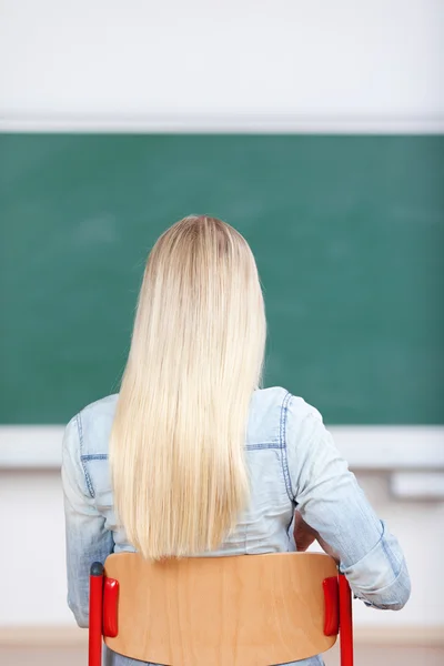 Estudante feminina sentada na cadeira contra o papelão — Fotografia de Stock