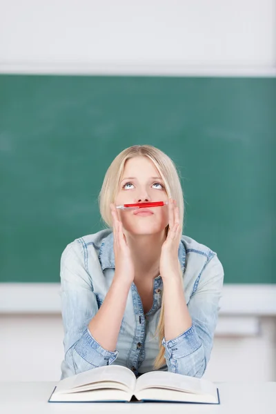 Studentin hält Stift als Schnurrbart über Lippen, während sie nach oben schaut — Stockfoto