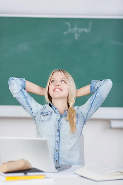 Estudiante con las manos detrás del día de la cabeza soñando en el escritorio —  Fotos de Stock