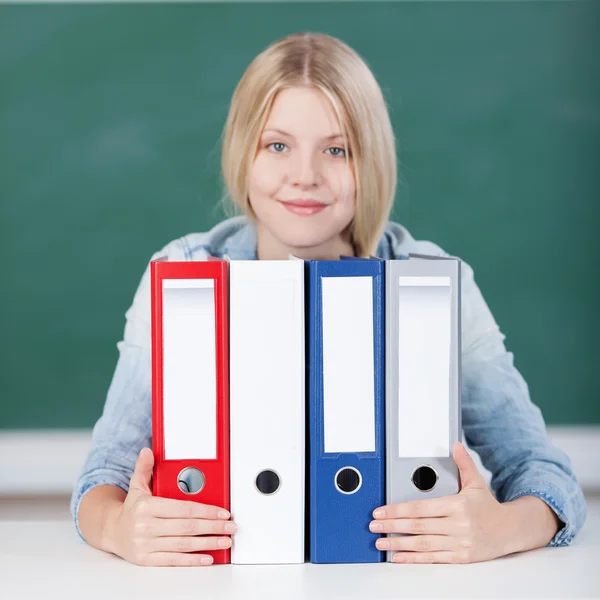 Vrouwelijke student met kleurrijke bindmiddelen op Bureau in klas — Stockfoto