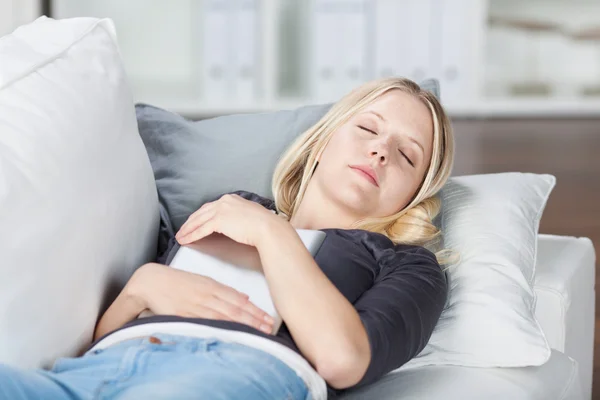 Женщина с цифровой таблеткой спит на диване — стоковое фото
