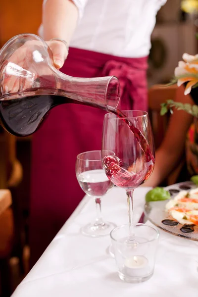 Garçonete derramando vinho tinto — Fotografia de Stock