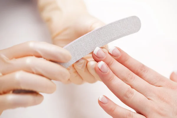 Beautician filing a clients fingernails — Stock Photo, Image
