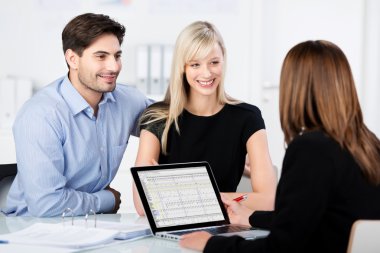 Couple Smiling While Looking At Financial Advisor At Desk clipart