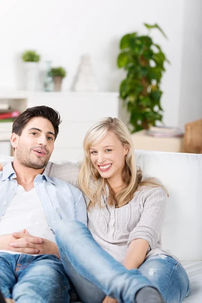 Casal feliz sentado no sofá em casa — Fotografia de Stock