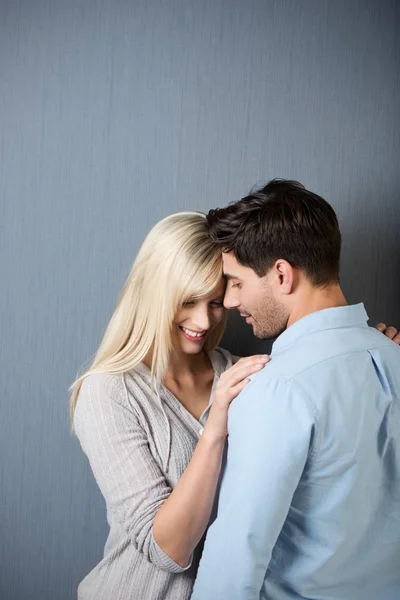 Pareja amorosa de pie contra la pared azul — Foto de Stock