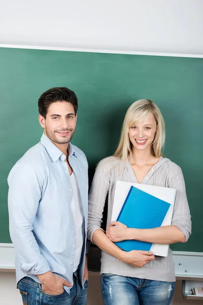 Teachers Standing Against Chalkboard In Classroom — Stock Photo, Image