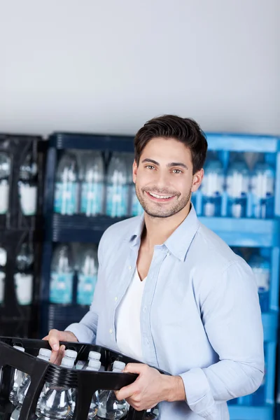 Mann trägt Kiste mit Wasserflaschen im Geschäft — Stockfoto