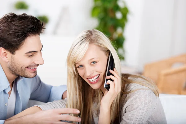 Mujer conversando por teléfono inalámbrico mientras el hombre la mira —  Fotos de Stock