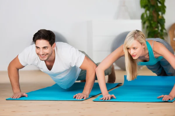 Jovem casal fazendo press-ups em um ginásio — Fotografia de Stock