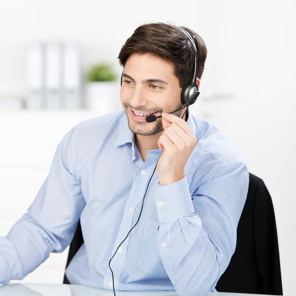 Operador de servicio al cliente que comunica en auriculares en el escritorio —  Fotos de Stock