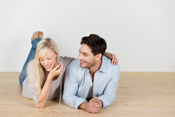 Laughing young couple lying on the floor — Stock Photo, Image