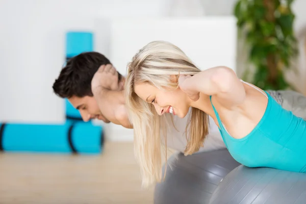 Mujer haciendo ejercicio en la bola de pilato con el hombre en casa — Foto de Stock