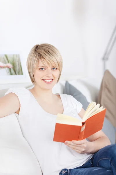 Kobieta czytająca książkę na kanapie — Zdjęcie stockowe