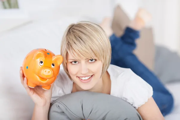 Smiling young woman holding up a piggy bank — Stock Photo, Image