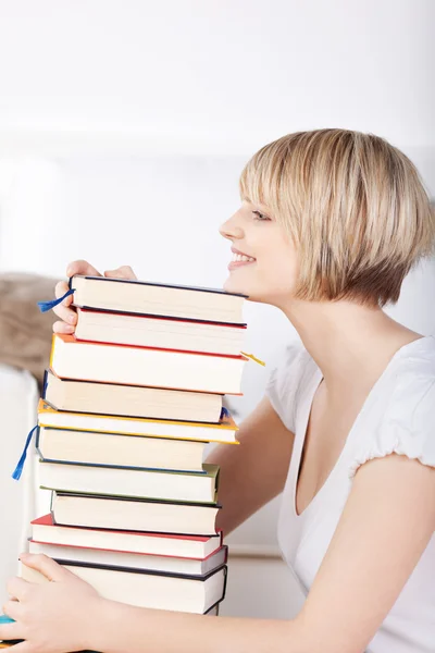 Gelukkige vrouw met een enorme stapel boeken — Stockfoto