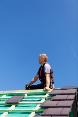 Roofer sitting on top of a roof clipart