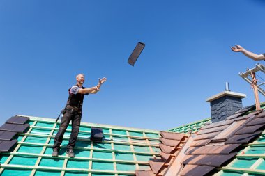 Two roofers tossing tiles clipart