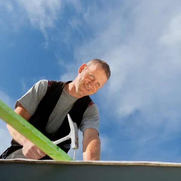 Smiling roofer hammering a nail — Stock Photo, Image