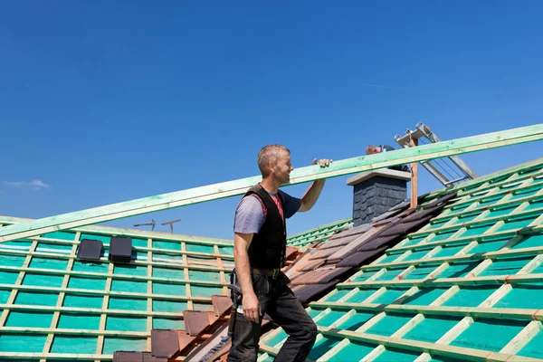 Roofer climbing the roof with a beam — Stock Image Roofer climbing the roof with a beam Royalty Free Stock Photos