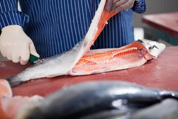 Travailleur coupe du poisson à la table — Photo