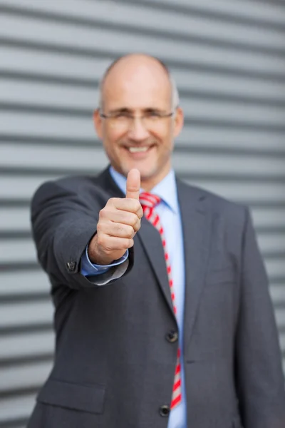 Empresário Gesturing Thumbs Up Against Shutter — Fotografia de Stock