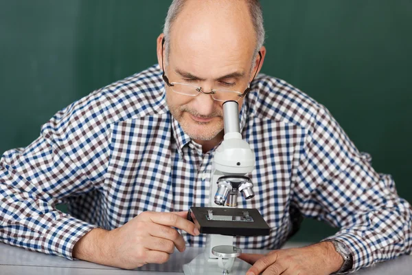 Homem olhando para baixo um microscópio — Fotografia de Stock