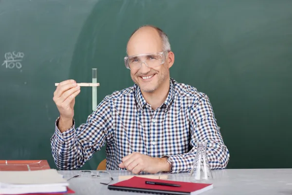 Laughing science teacher holding up a test tube — Stock Photo, Image