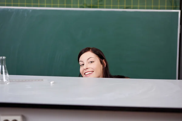 Joven estudiante de química escondido detrás de la mesa — Foto de Stock