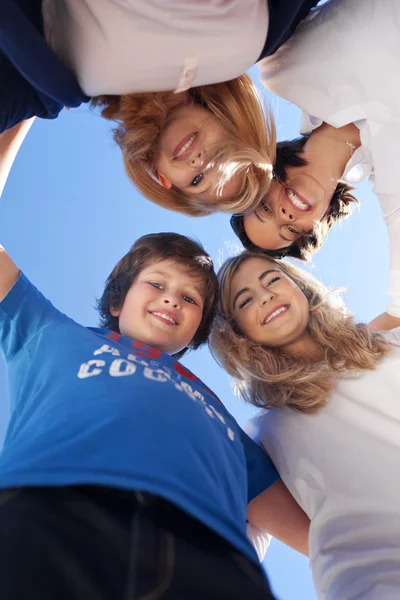 Kinderen en leraar vormen huddle tegen duidelijke blauwe hemel — Stockfoto