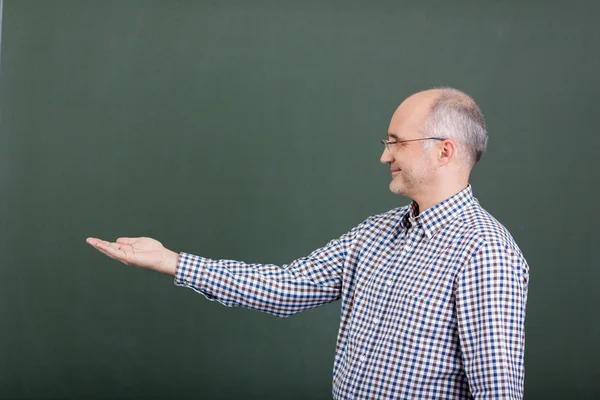 Profesor mostrando producto invisible contra pizarra —  Fotos de Stock