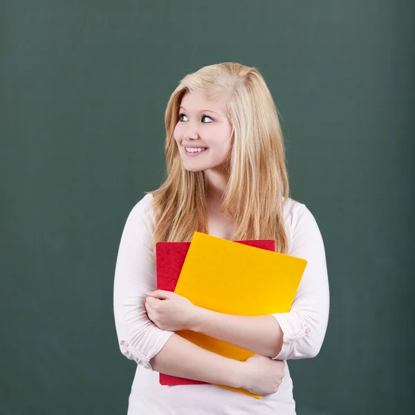 Doordachte tienermeisje houden bestanden tegen schoolbord — Stockfoto